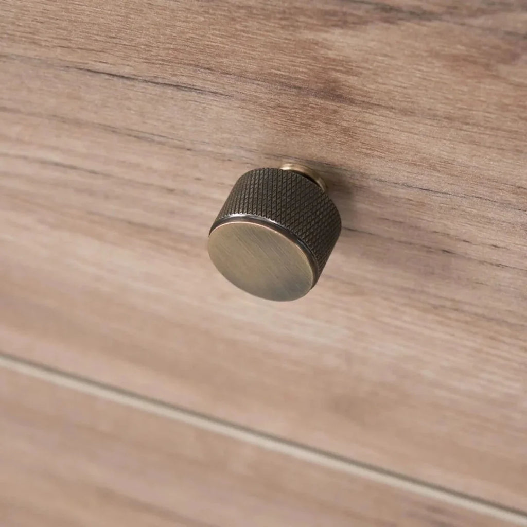 Wardrobe knob detail on distressed oak drawer front, dark textured round handle.