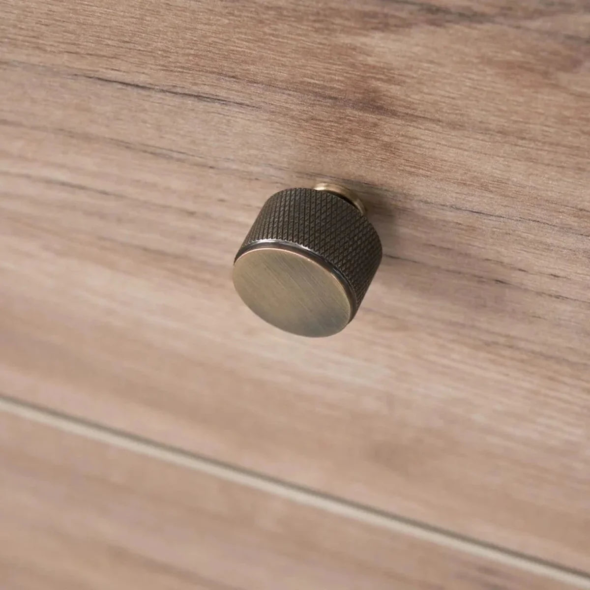 Wardrobe knob detail on distressed oak drawer front, dark textured round handle.