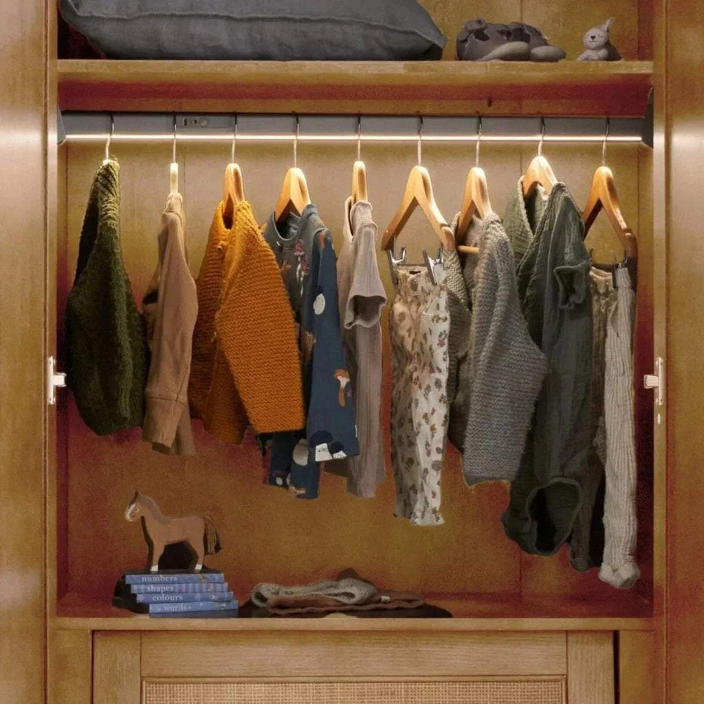 Open light oak wardrobe with hanging clothes on a central rail