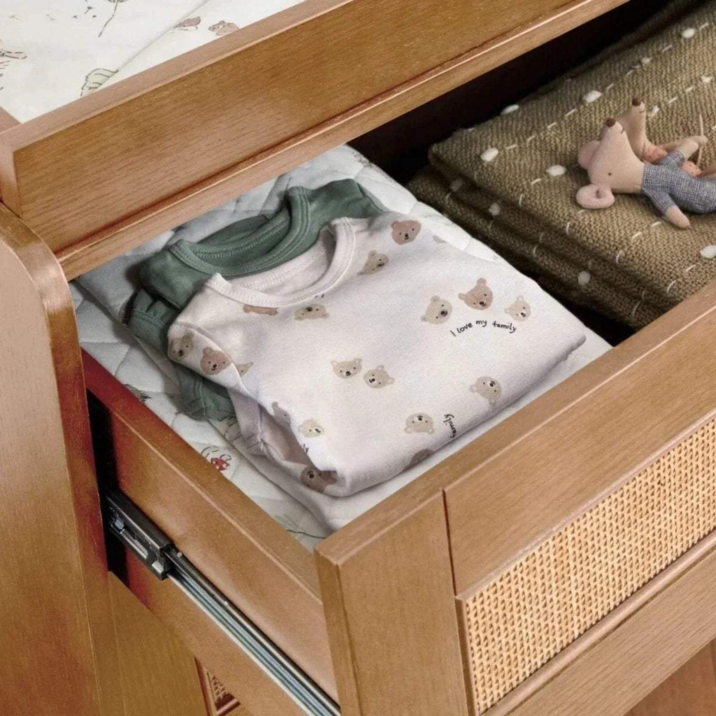 Light oak wardrobe drawer open with folded baby clothes and fabric divider