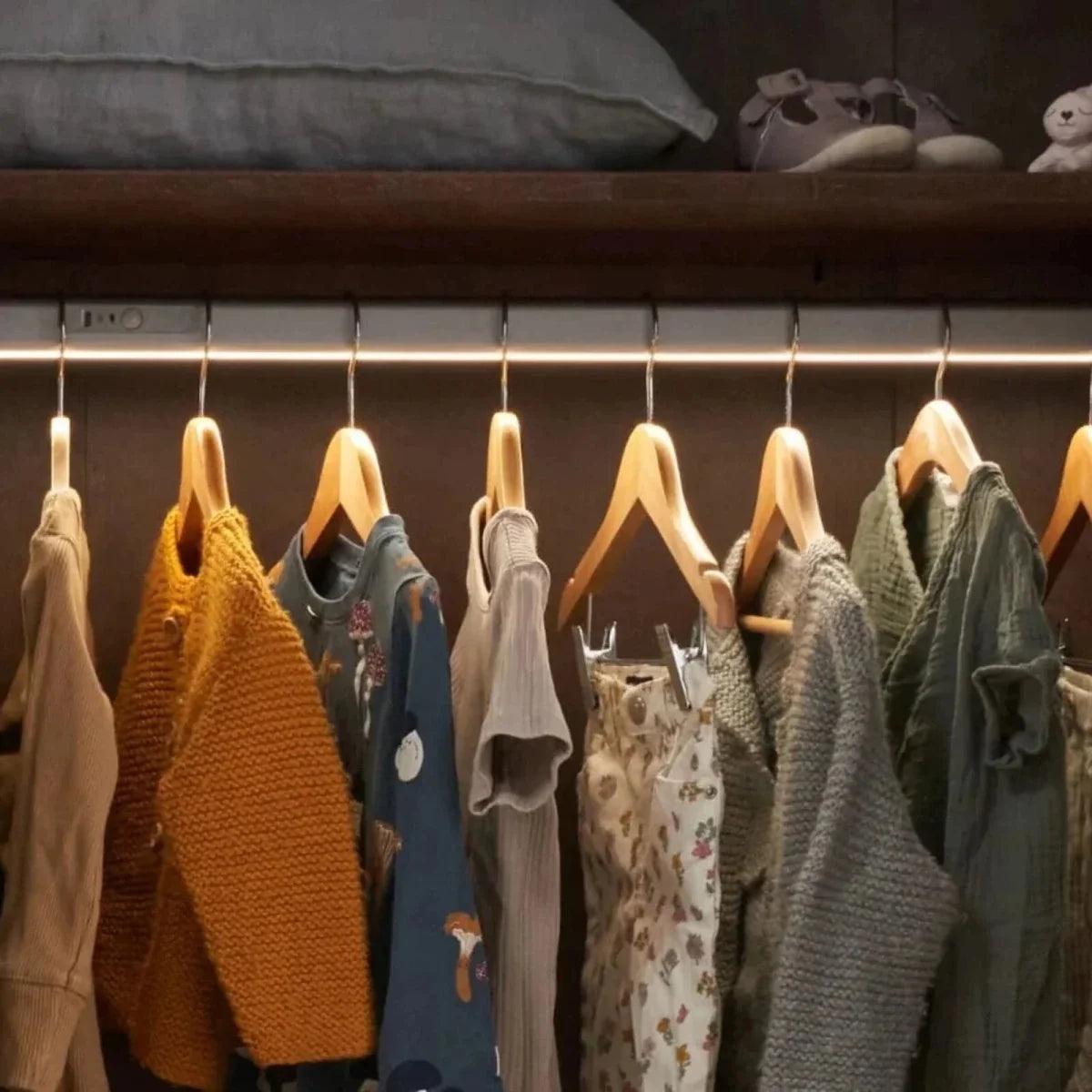 Wardrobe hanging rack with folded and hanging baby clothes in various colors