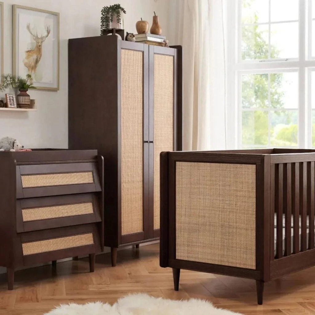 Warm walnut wardrobe with woven doors next to a matching cabinet and crib