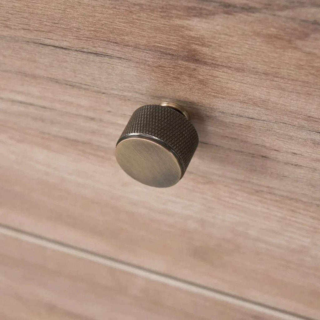 Round dark knob on light wood changing chest drawer front