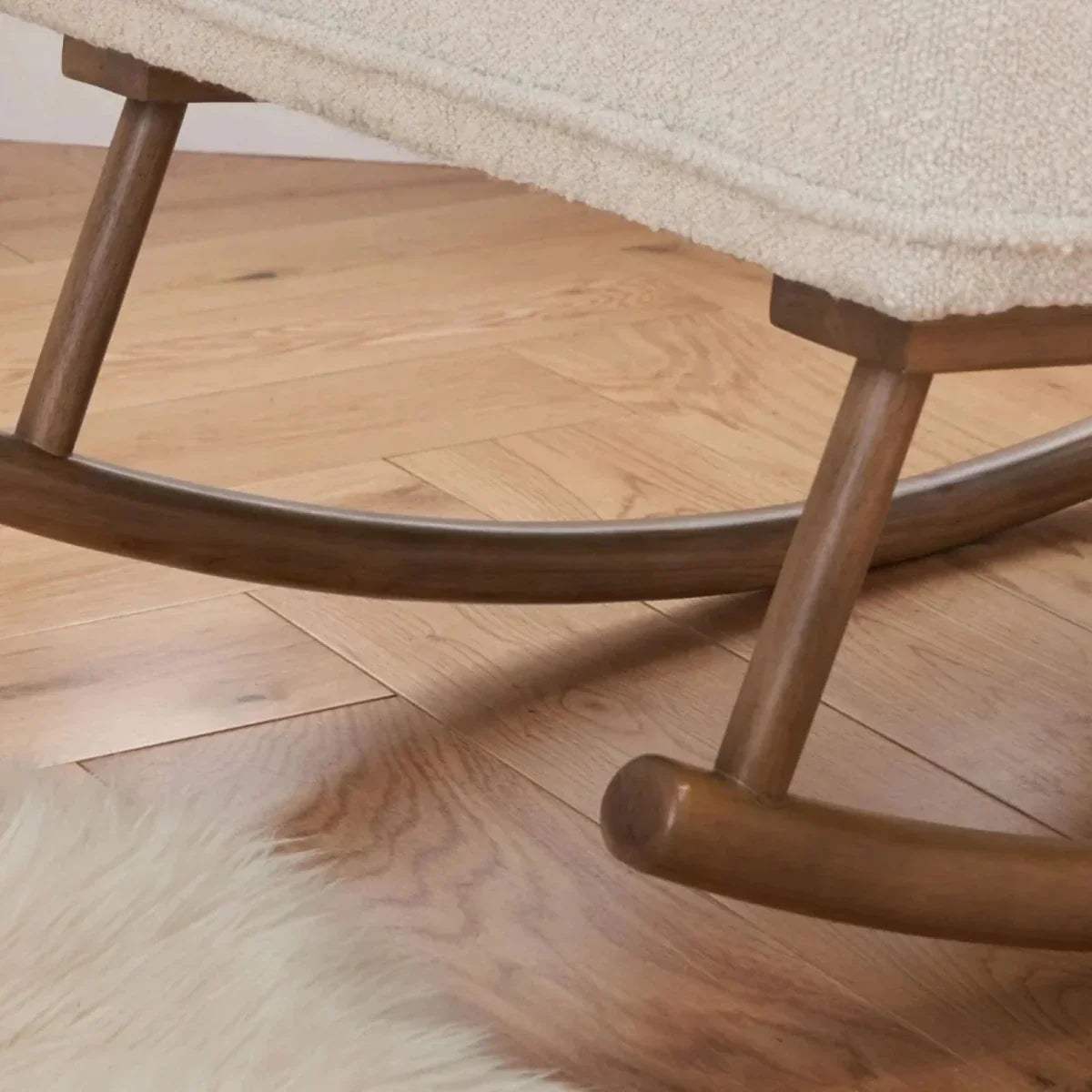 Close-up of wooden rocking base runners under fresh cream boucle chair