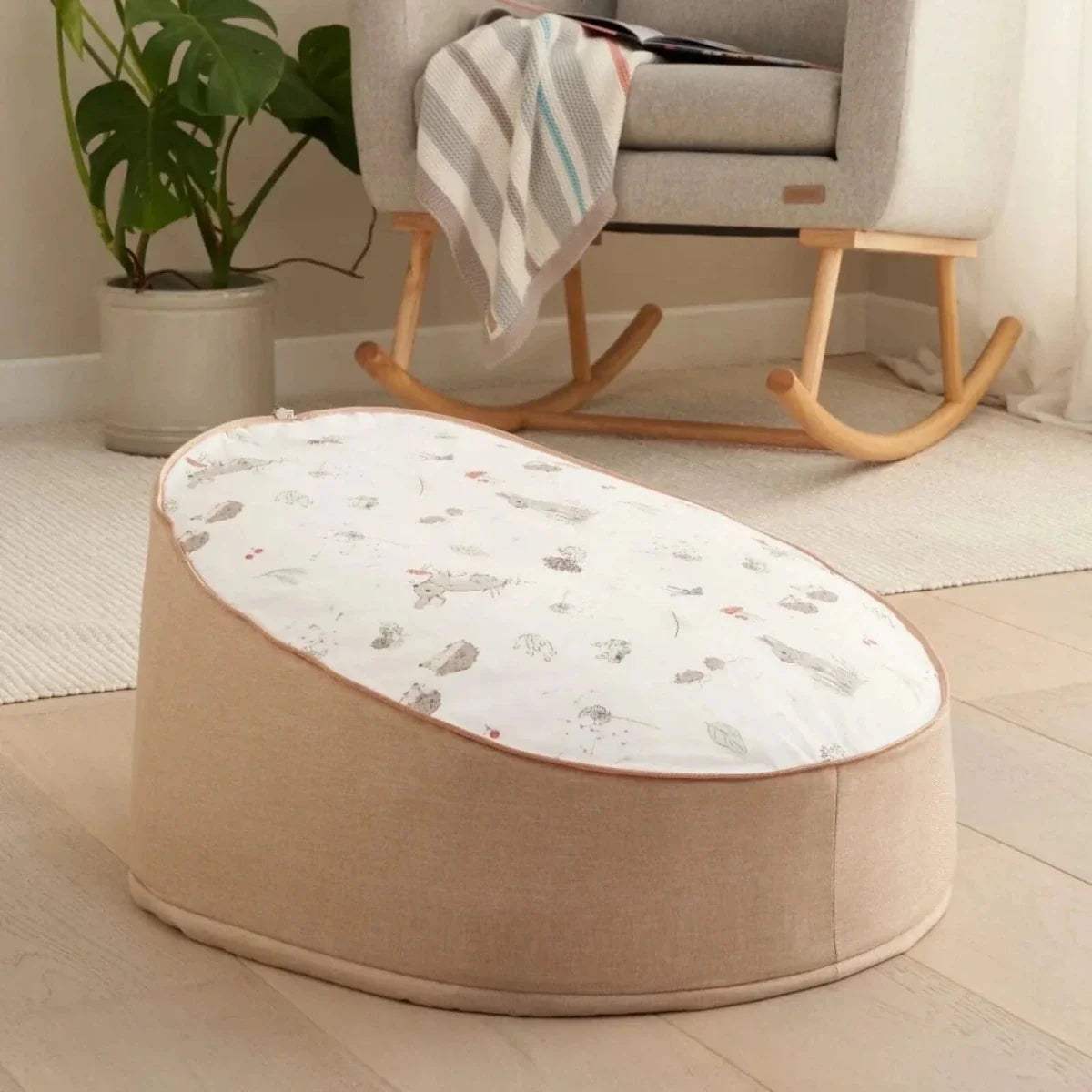 Low-profile round baby beanbag with taupe base and white animal-pattern cover