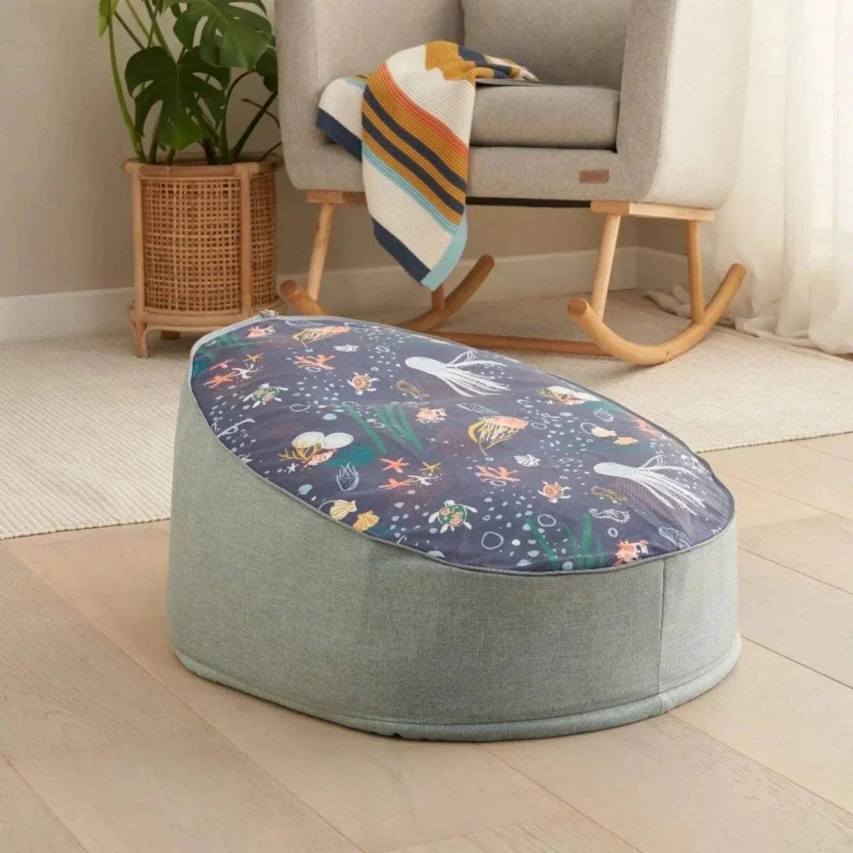 Baby beanbag with gray base and dark navy ocean animal print top, rounded seat shape.