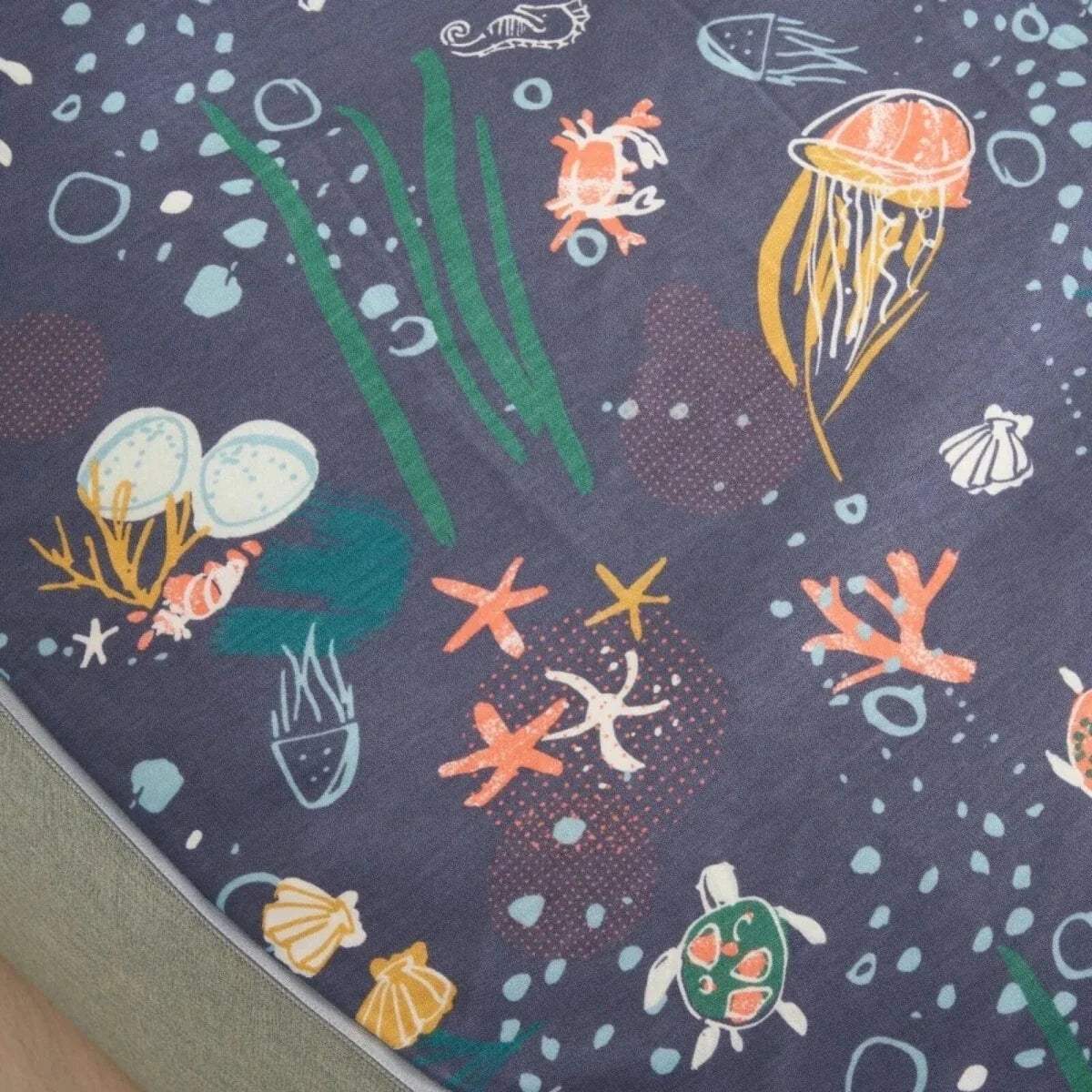 Close-up of navy ocean-pattern beanbag cover with jellyfish, fish, shells, and stars.
