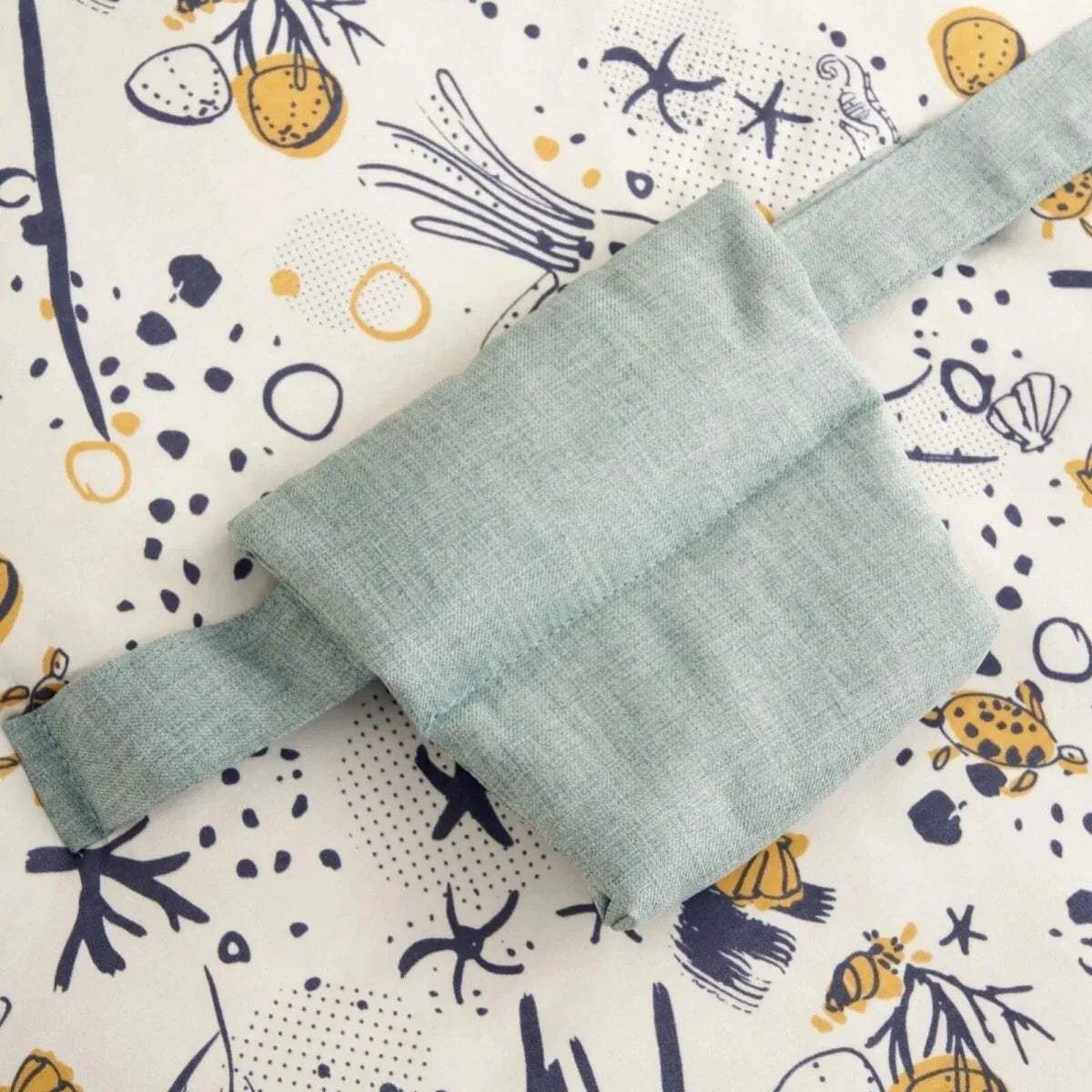 Ocean-print beanbag cover fabric with pale blue patch and stitched seam details.