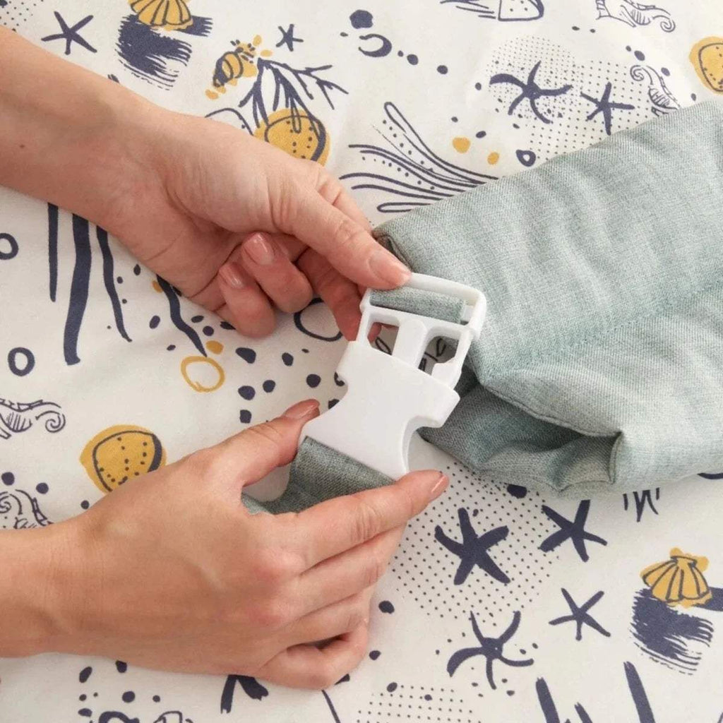 Zip tab and hands opening a pale blue zipper on an ocean-print baby beanbag cover.