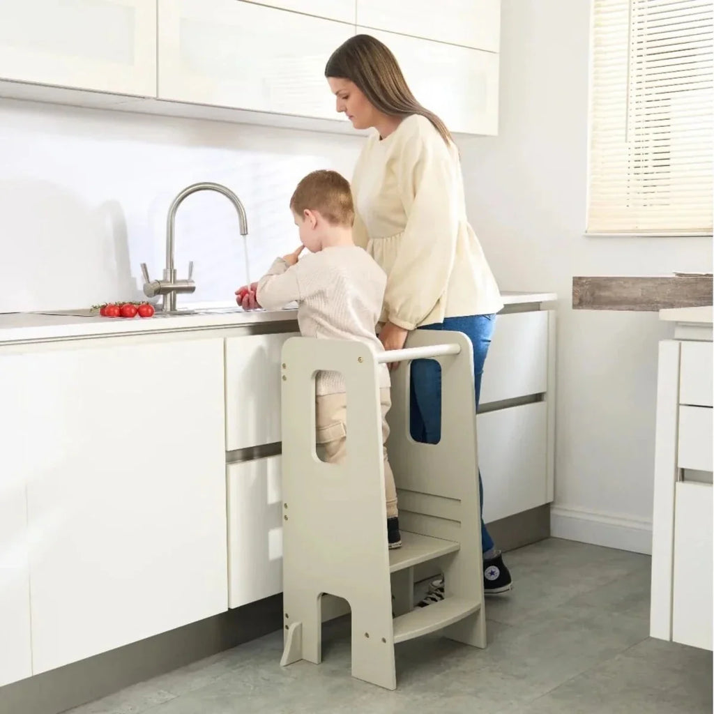 Light beige learning tower in kitchen setting with toddler standing on lower step