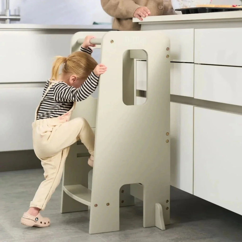Light beige Montessori learning tower with toddler on step and adult assisting