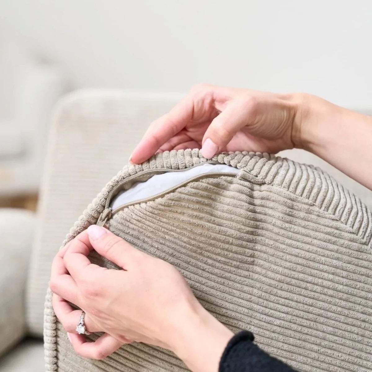Hands adjusting textured mushroom-beige cushion cover on children’s play sofa