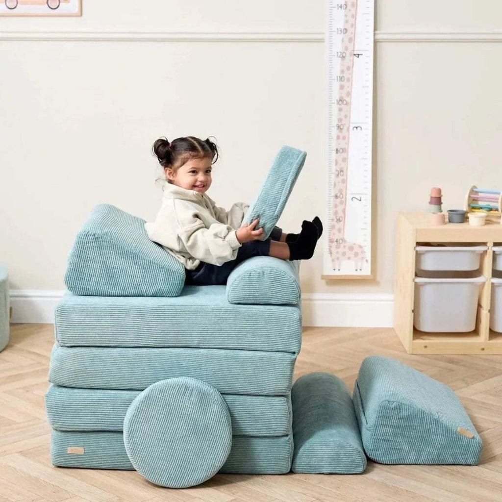 Kids play sofa with child sitting on back cushion, teal bolsters and round floor pads