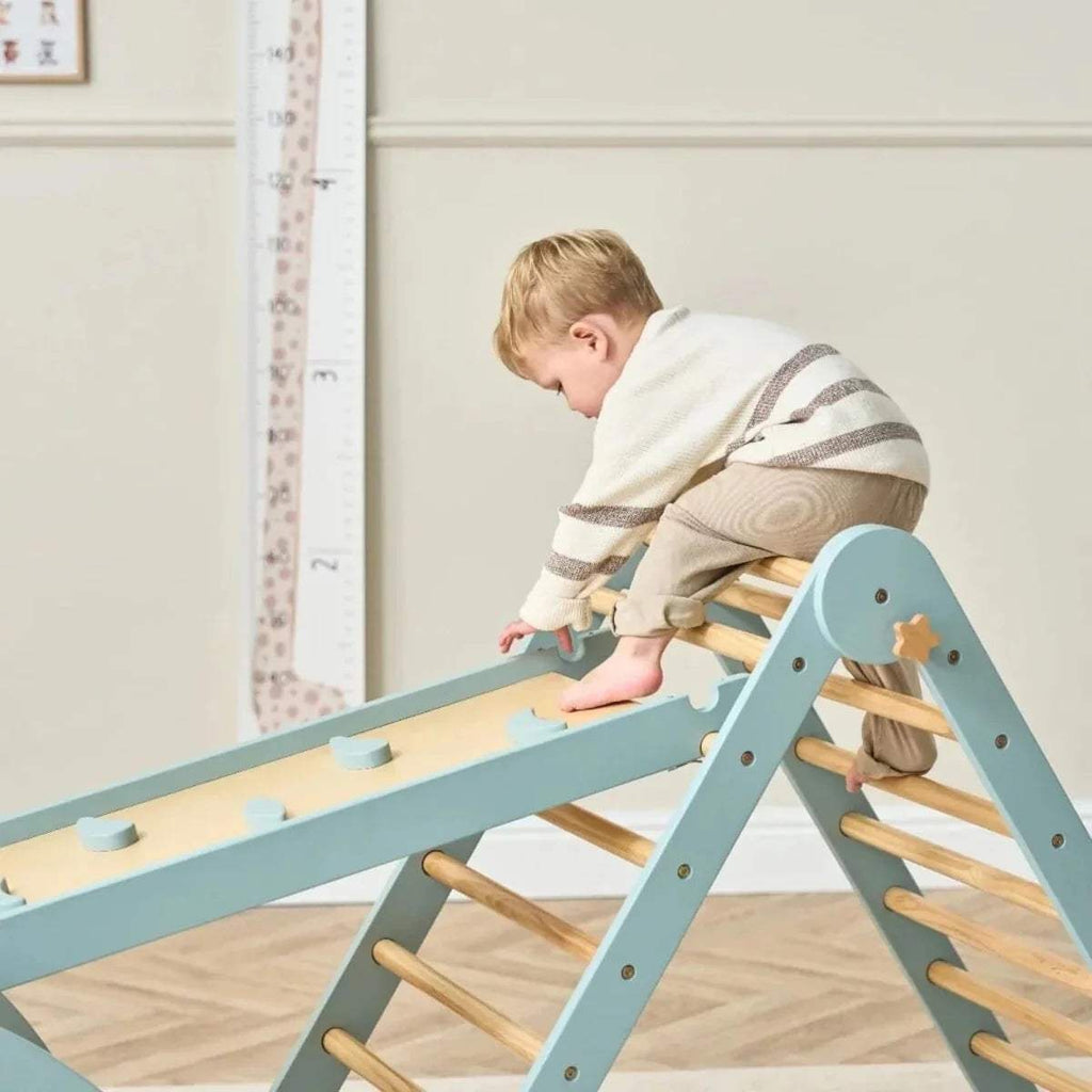 Child climbing on Pikler ramp with wooden rungs and ocean stone frame