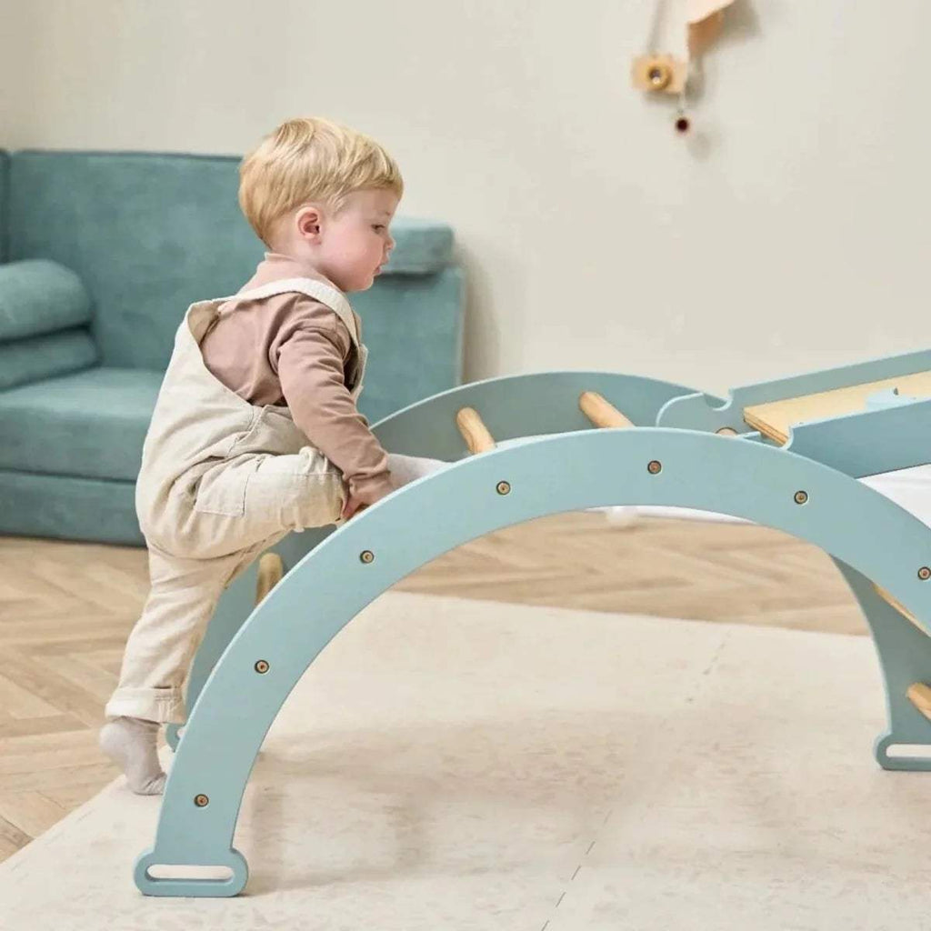 Child beside arched base of ocean stone Pikler climbing frame with wooden rungs