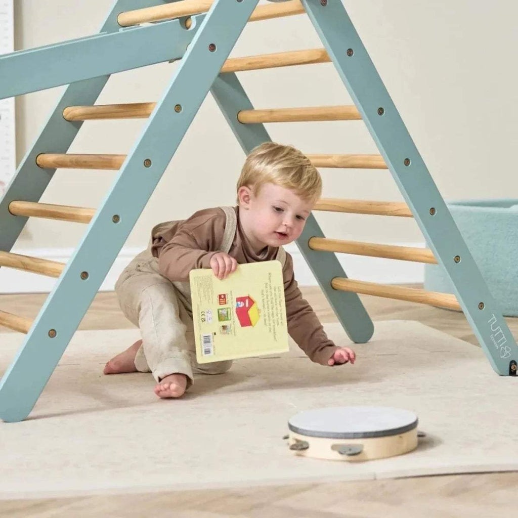 Child crawling on floor beside ocean stone Pikler ladder with wooden rungs