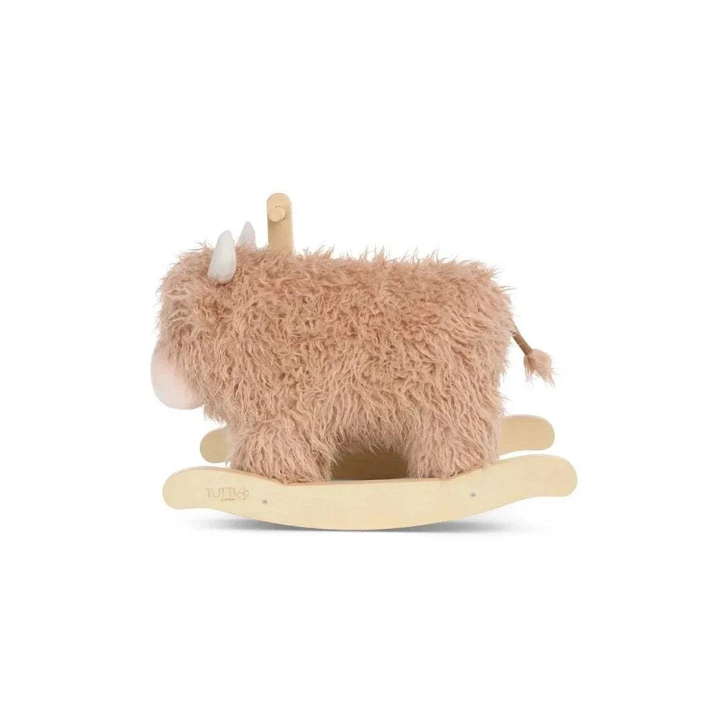 Highland cow rocking toy side view: beige plush body, white snout, wooden rocker base.