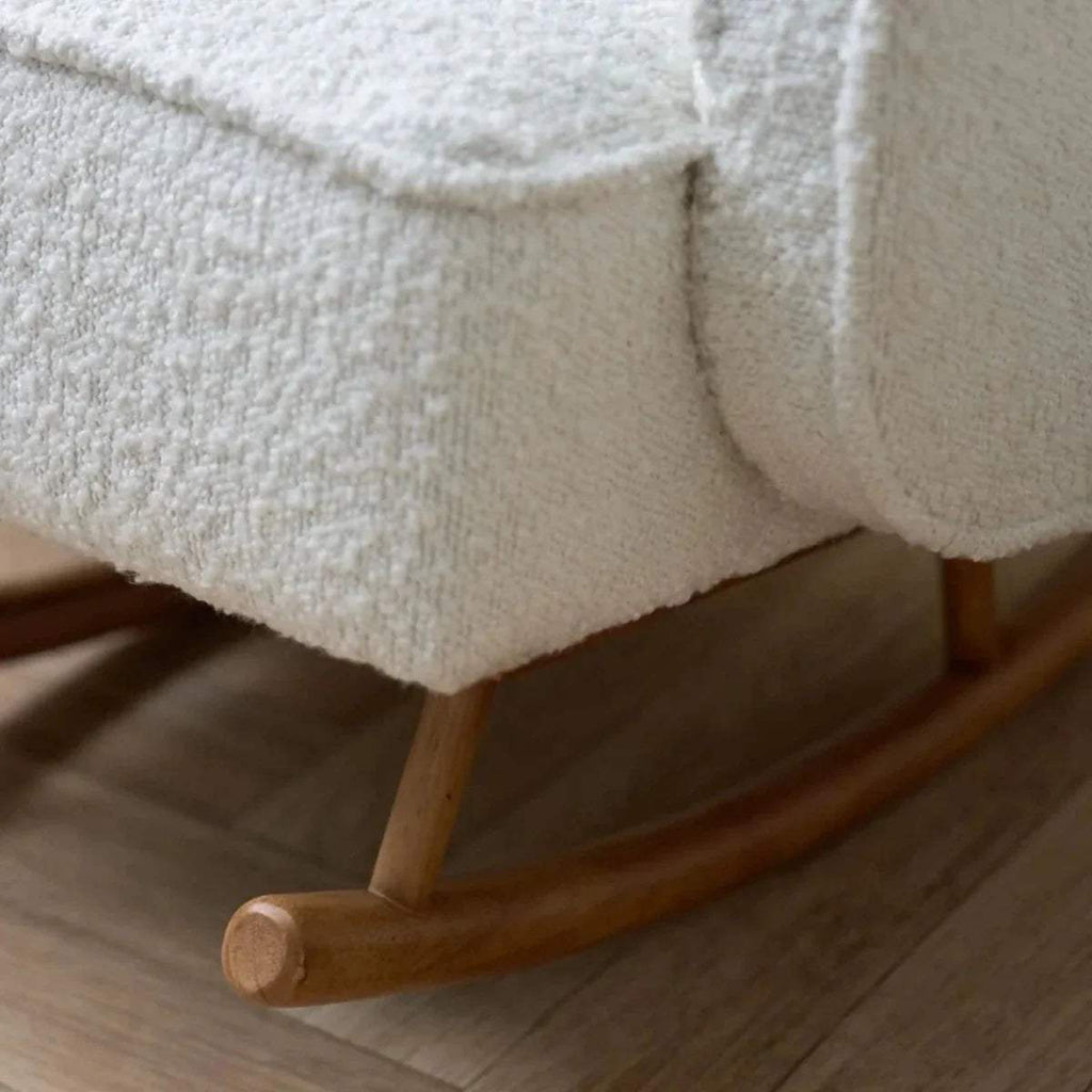 Close-up of cream upholstered rocking chair base with wooden rocker and legs