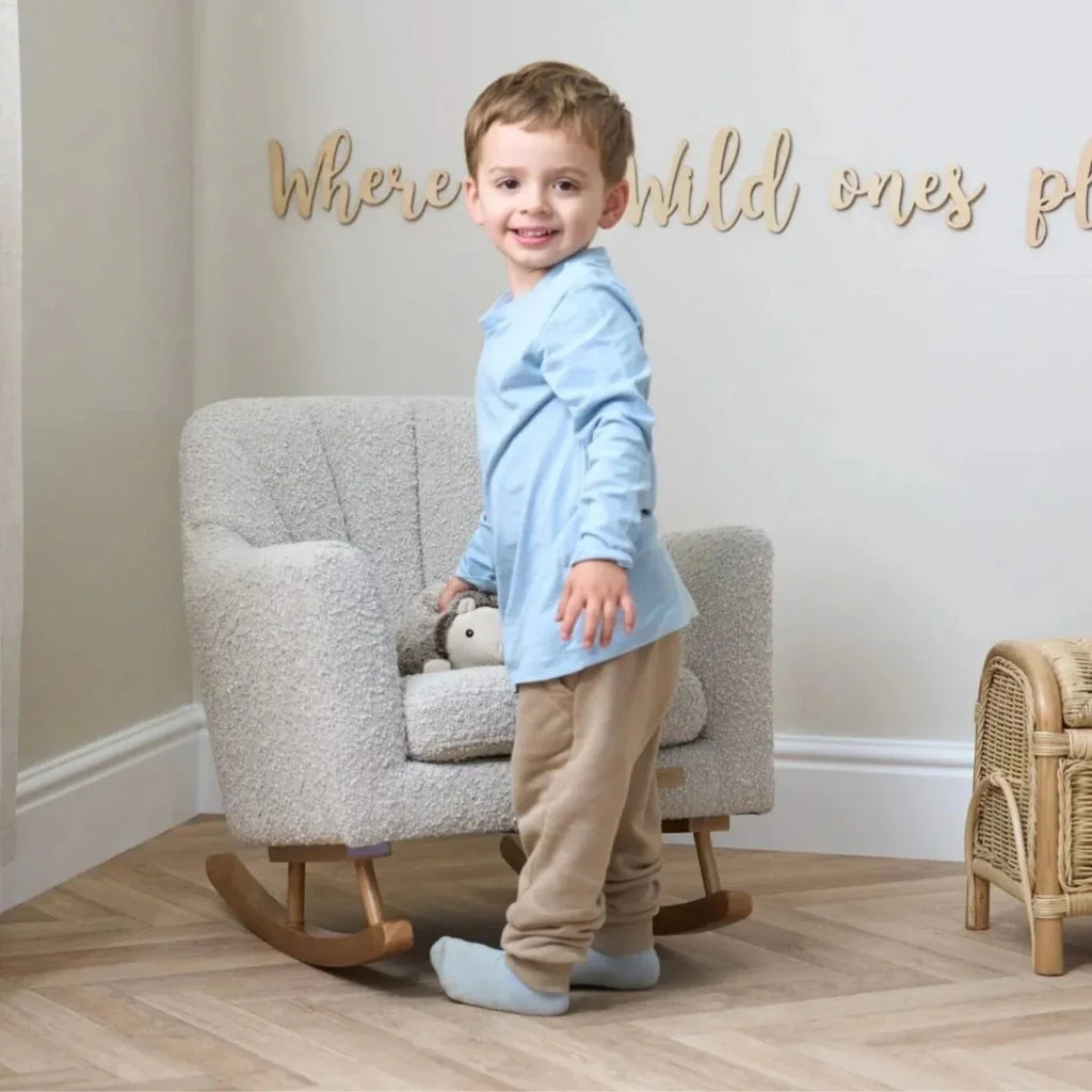 Children's light-cream boucle rocking chair with child sitting beside a plush toy