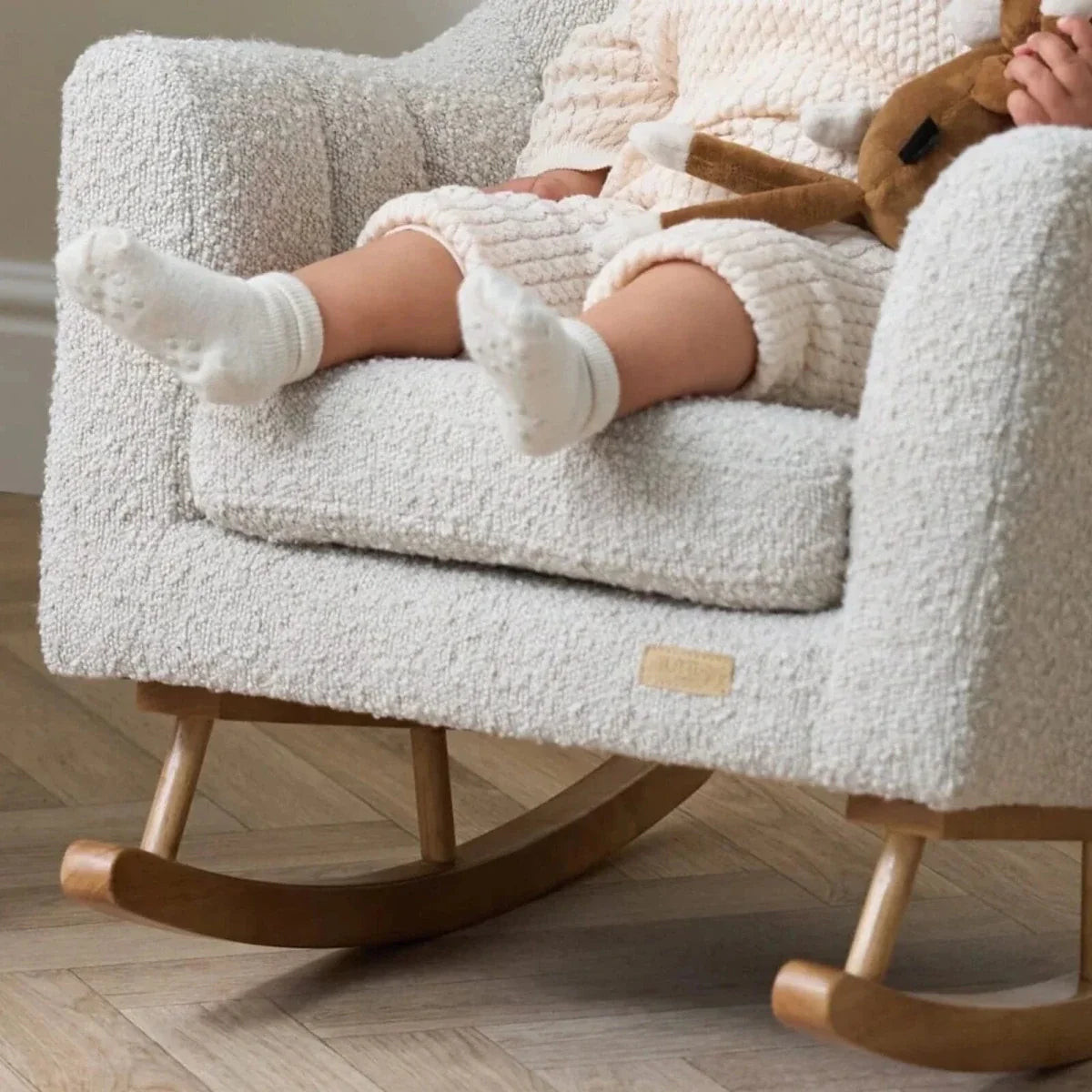 Light-cream boucle rocking chair with wooden rockers and close-up of cushioned arm
