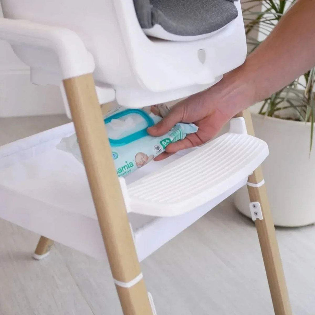 White highchair with gray seat and footrest; hands place items on tray