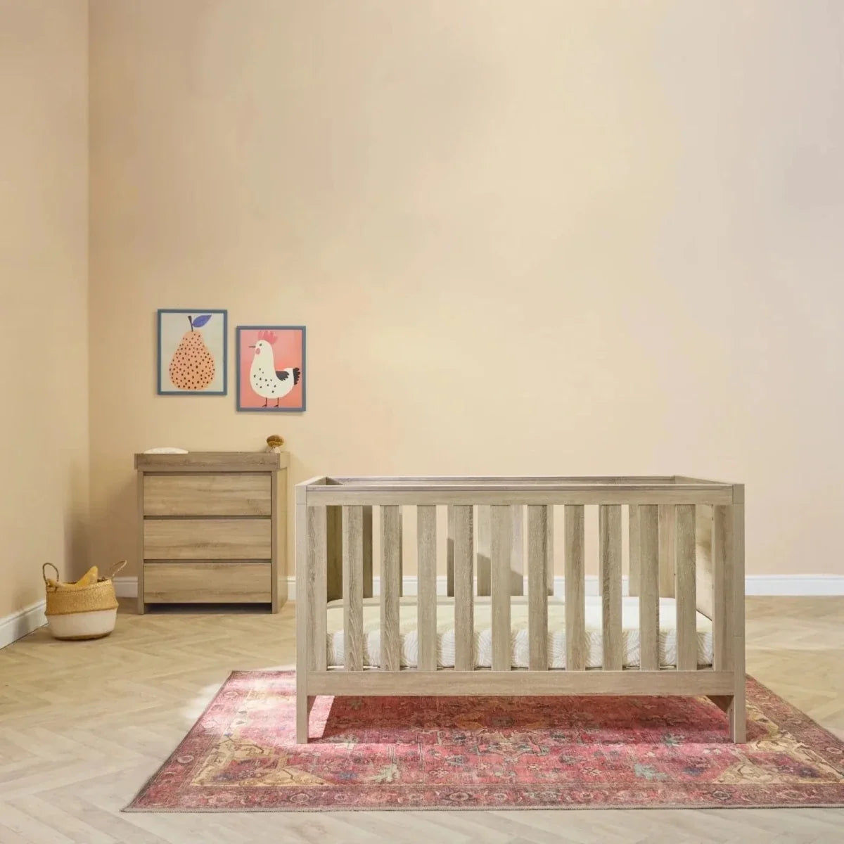 Light oak cot bed with tall side rails and matching dresser with three drawers.