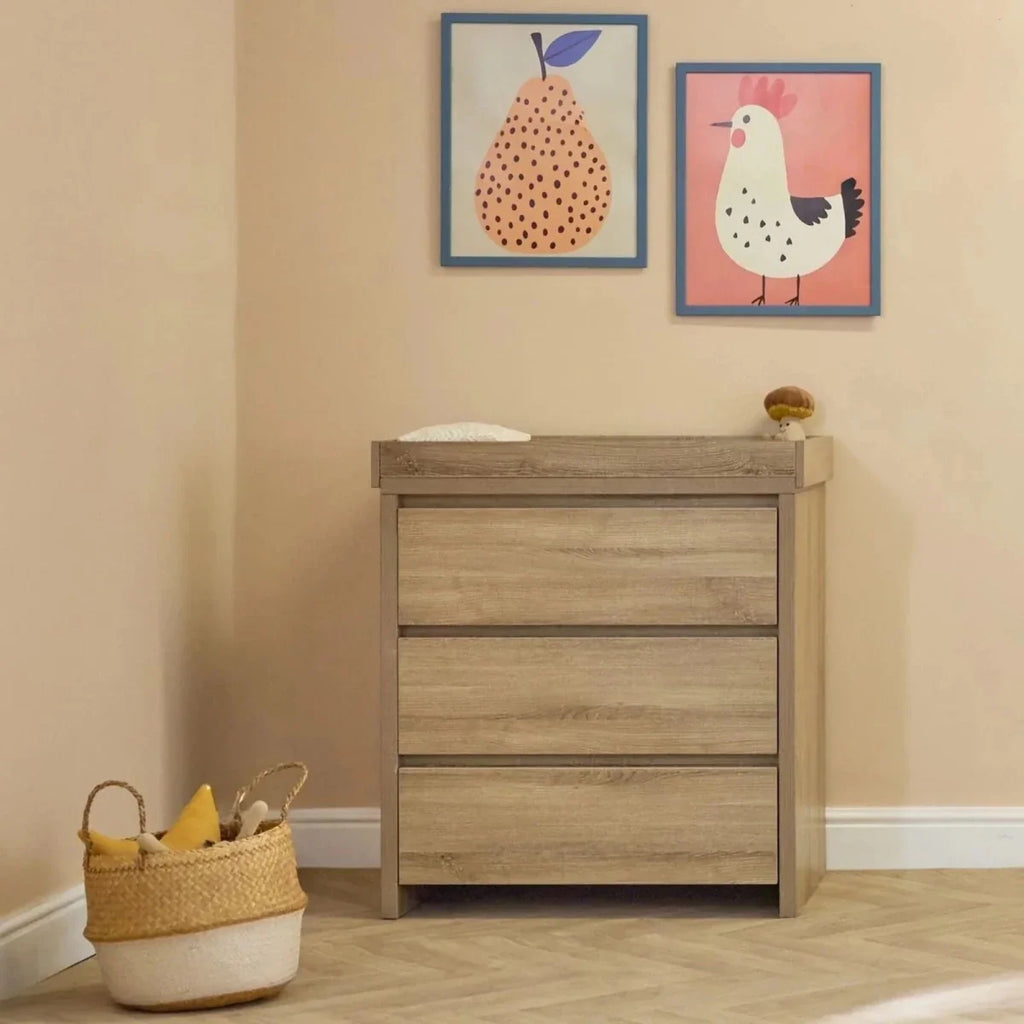 Light oak dresser with three drawers next to an oak cot bed with side rails.