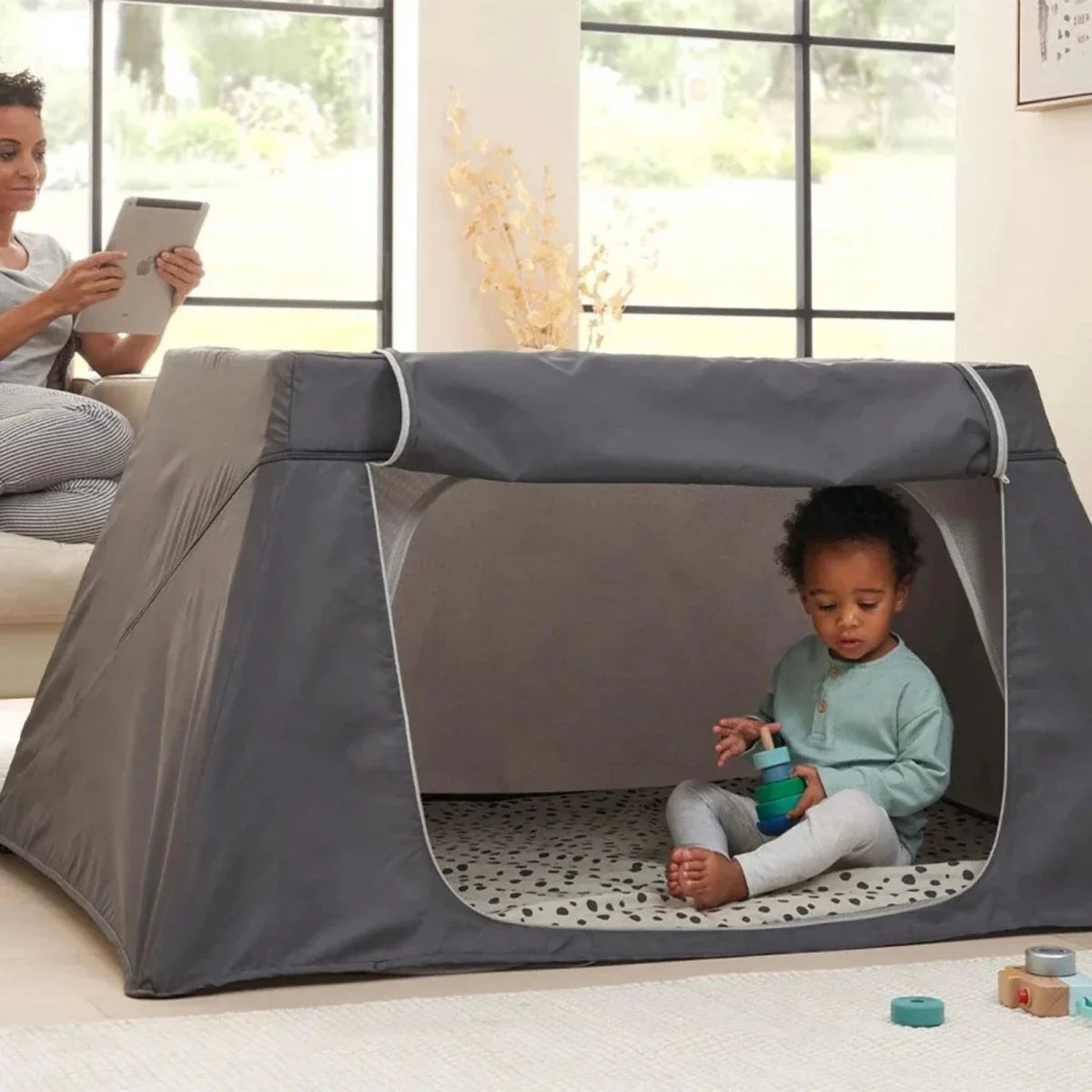 Grey fabric travel cot playpen with zip mesh window and padded frame