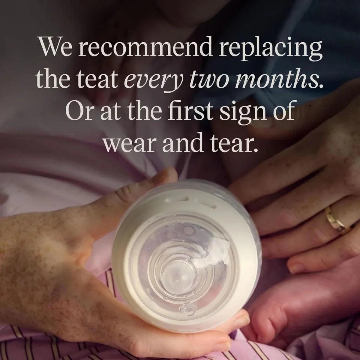 Baby bottle with teat held by hands, bottle top opened