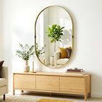 Gold-tone oval wall mirror with slim elevated frame and clear reflective surface