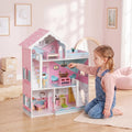Pink wooden 3-storey dollhouse with child playing at the lower level