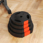 Stack of black weight plates with orange corner blocks, three top grip holes