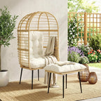 Beige rattan egg chair with white cushion and matching footstool, draped throw