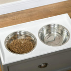 Close-up of grey raised feeding station with two stainless steel bowls and drawer handle.
