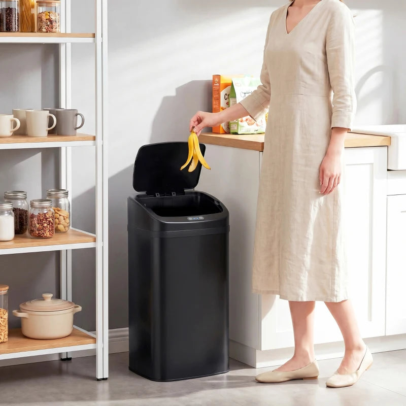Black 48 L sensor bin in kitchen setting with open lid while user drops waste.