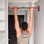 Man doing a pull-up on a red-and-black doorway bar with secure grips