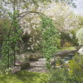 Black metal garden arch trellis with climbing vines near garden walkway