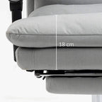 Grey upholstered office chair with footrest, close-up of thick armrest and seat cushion