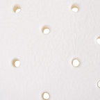 White shower stool seat surface close-up with evenly spaced drainage holes.