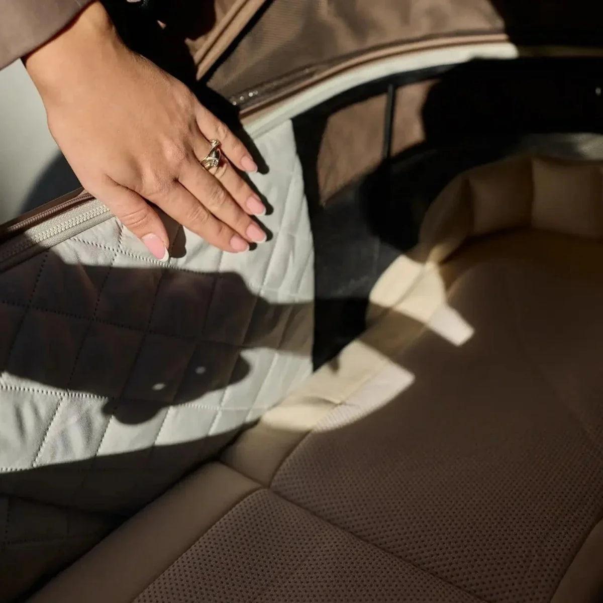 Beige stroller seat cushion with quilted fabric, hand adjusting fabric panel
