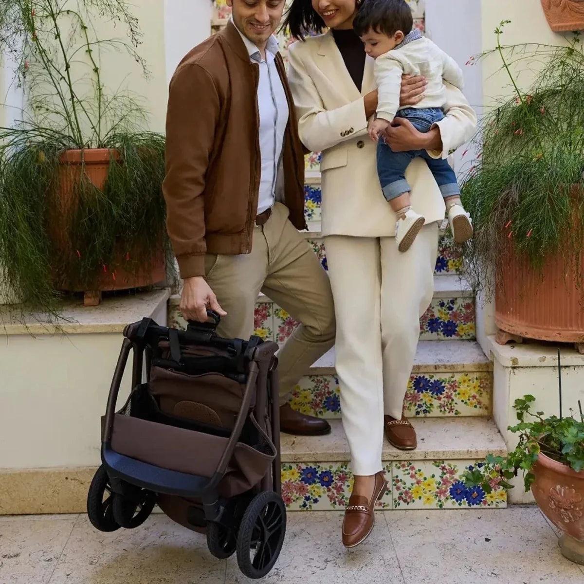 Black and tan 3-in-1 stroller parked on steps with carrycot attached