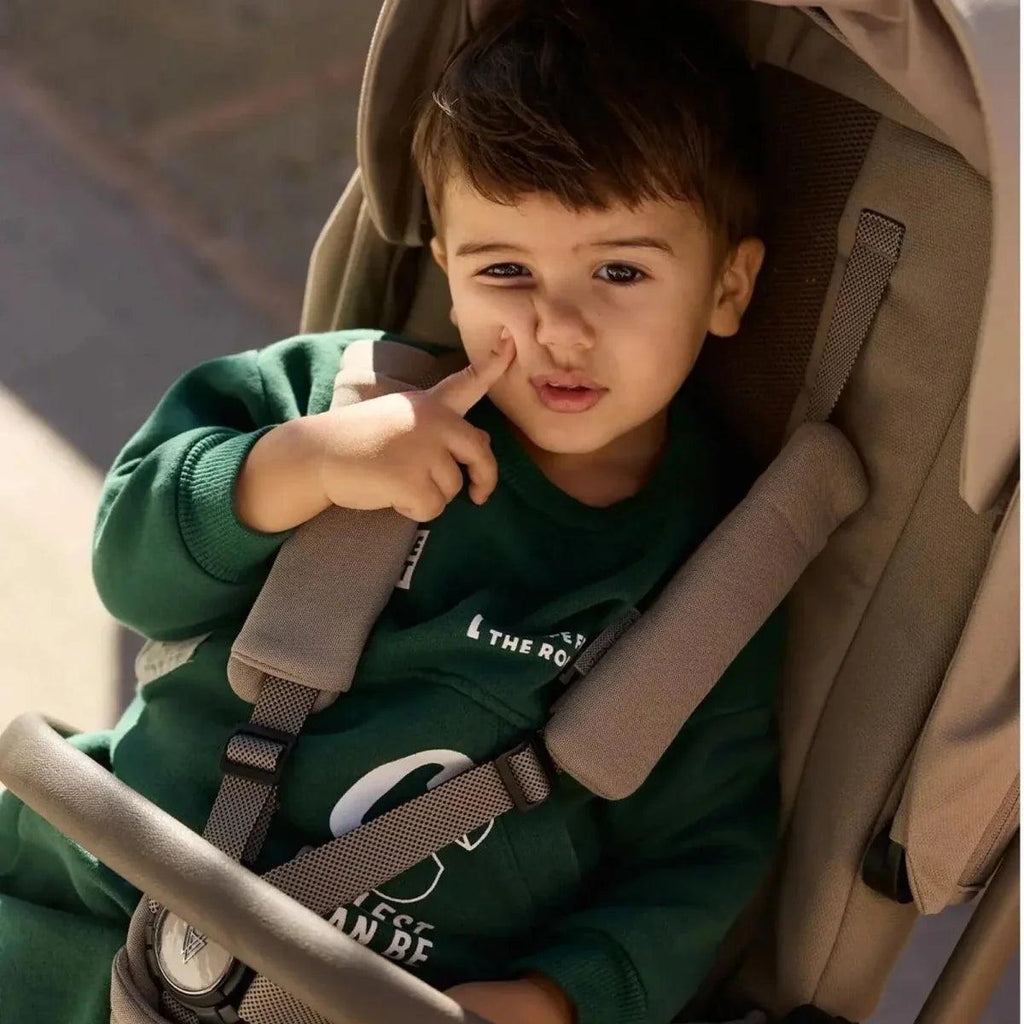 Black stroller seat close-up with child and five-point safety harness
