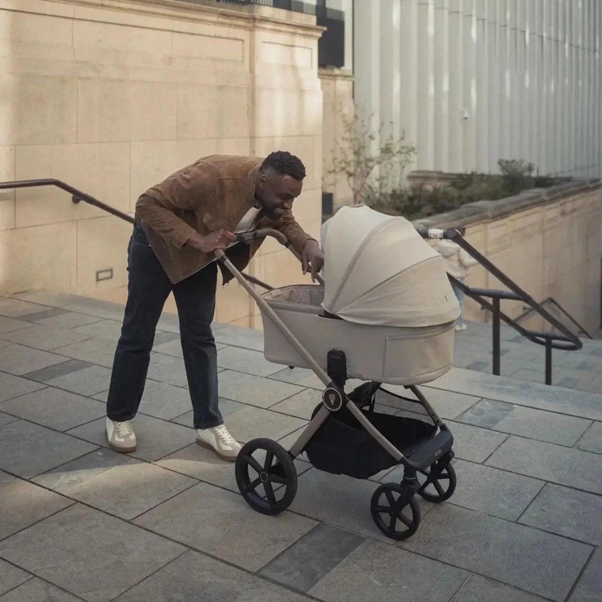 Baby stroller with cream carrycot and canopy on four large wheels