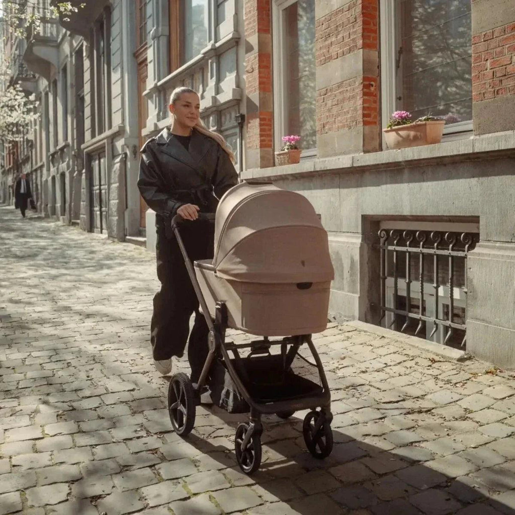 Beige pram bassinet with black stroller frame and wheels