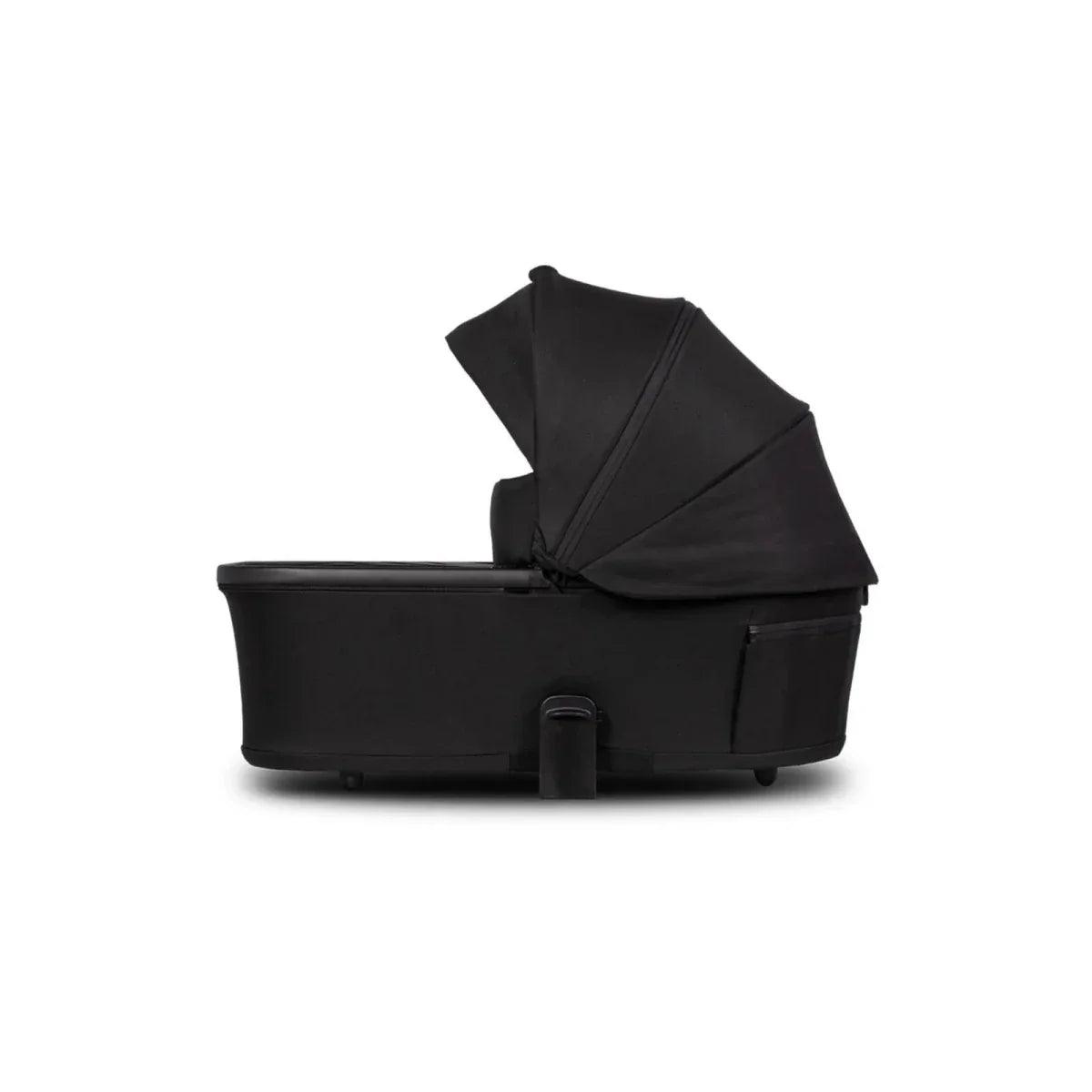 Black carrycot with fitted hood and side handle, shown in profile