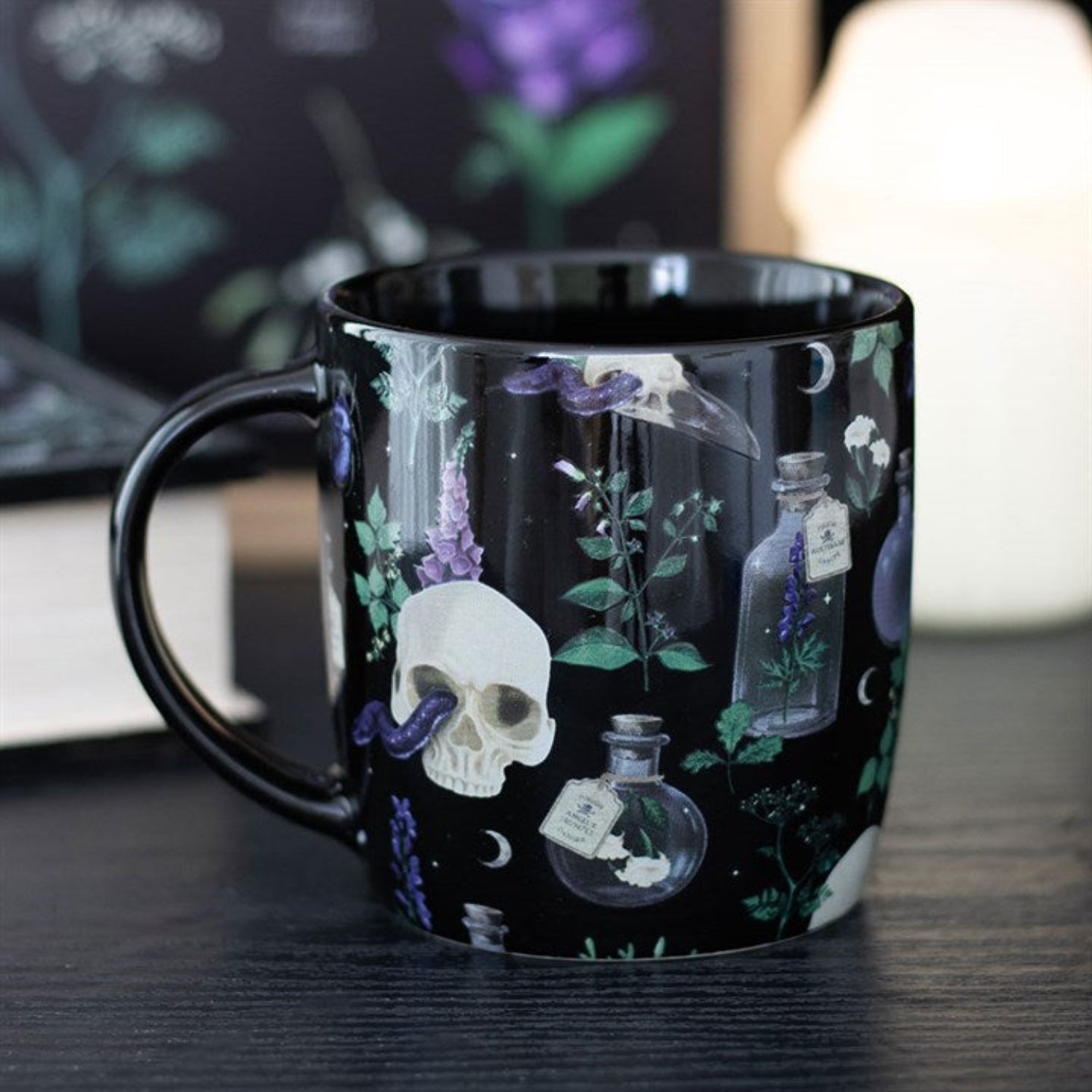 Black mug with skull and potion bottle design on a wooden surface