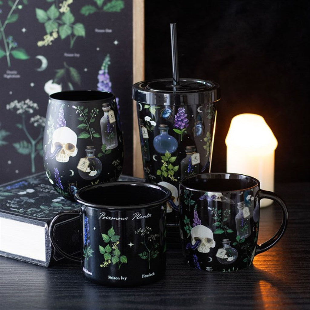 Set of black mugs with botanical and skull designs on a dark surface.