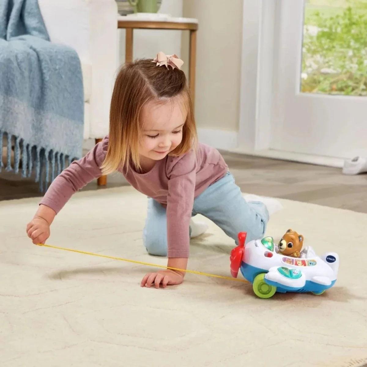 Toddler pulling VTech baby aeroplane pull toy with yellow string on floor