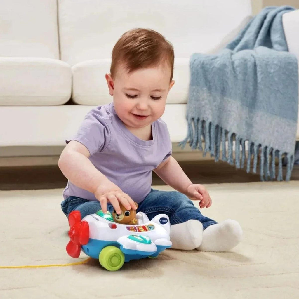 Child playing with VTech baby aeroplane pull toy on the sofa