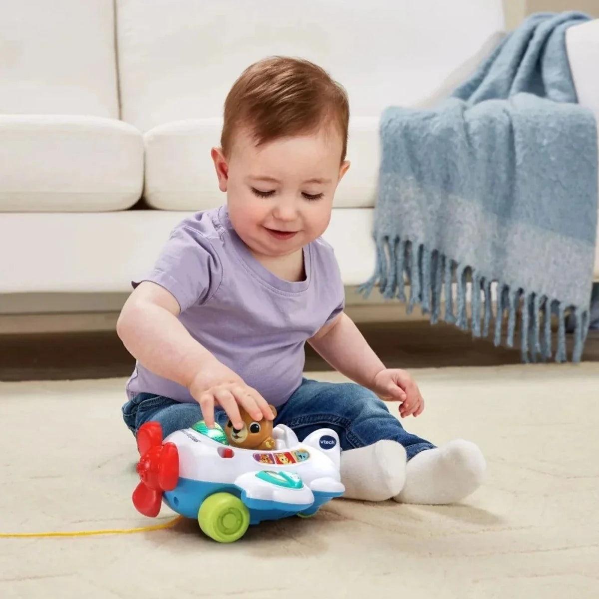 Child playing with VTech baby aeroplane pull toy on the sofa